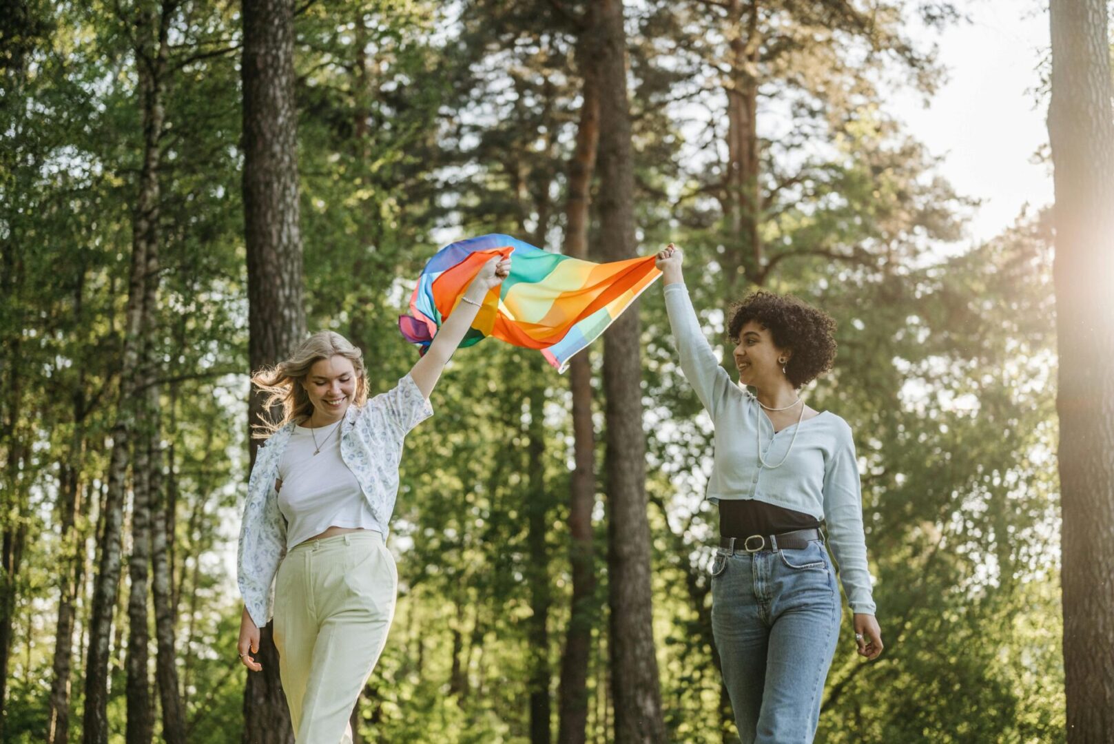 Two women are holding a kite in the woods.